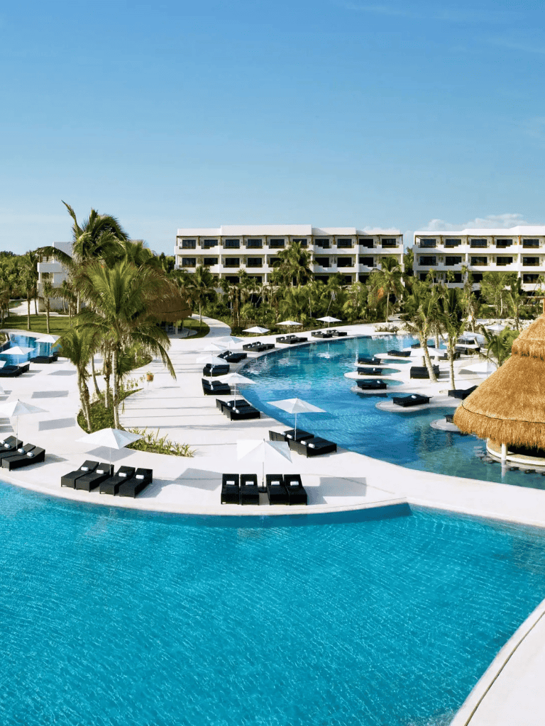 Luxury resort pool with palm trees and cabanas, ideal for relaxing vacations in tropical destinations.