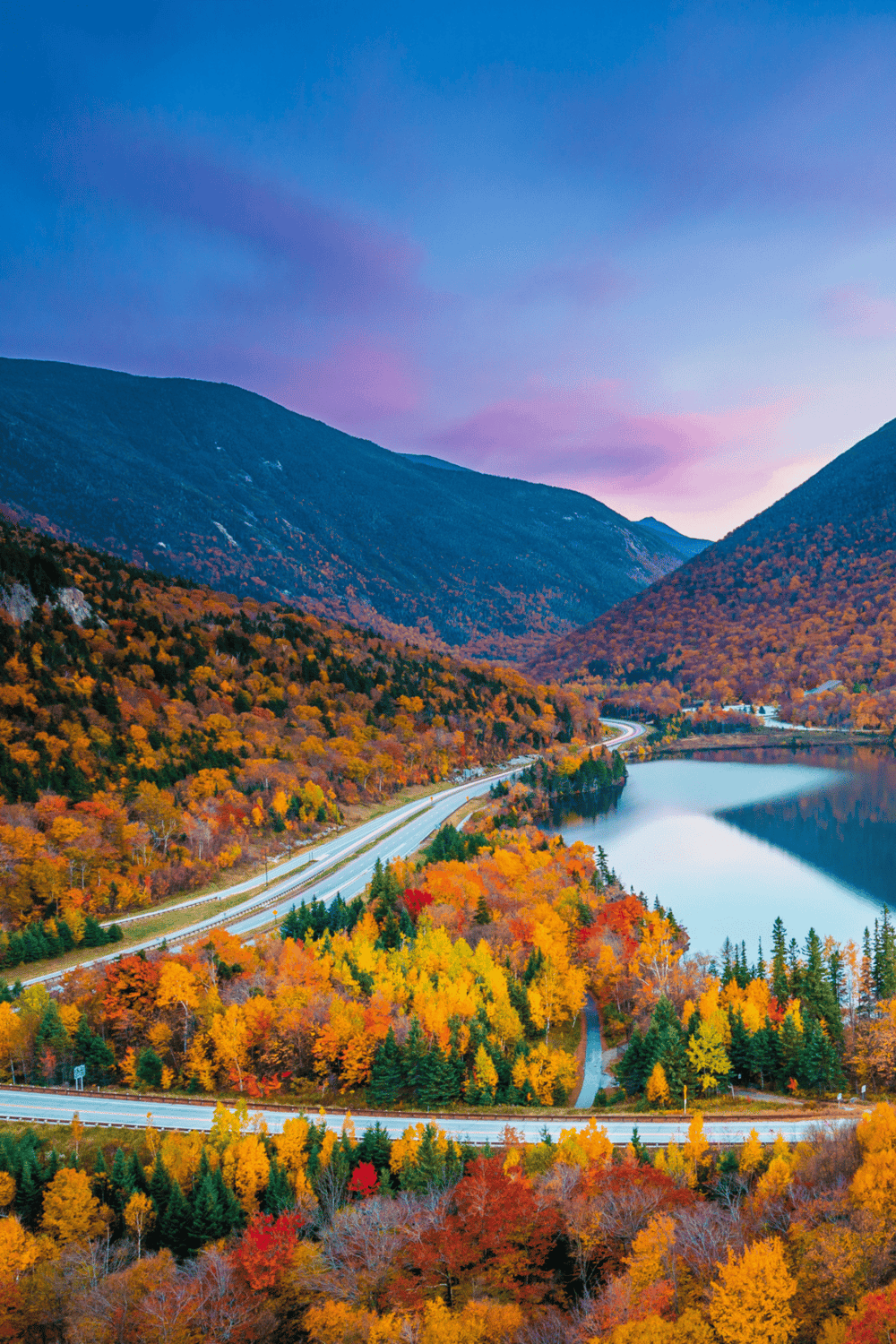 Colorful autumn mountain landscape with a winding road and lake, perfect for outdoor adventures.
