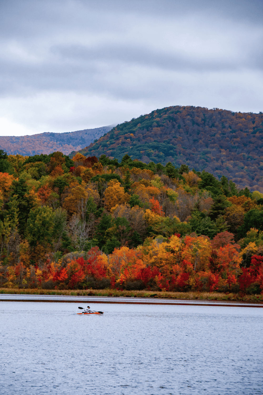 Vibrant autumn foliageAlong scenic lake with mountain backdrop, perfect for outdoor recreation and nature exploration.