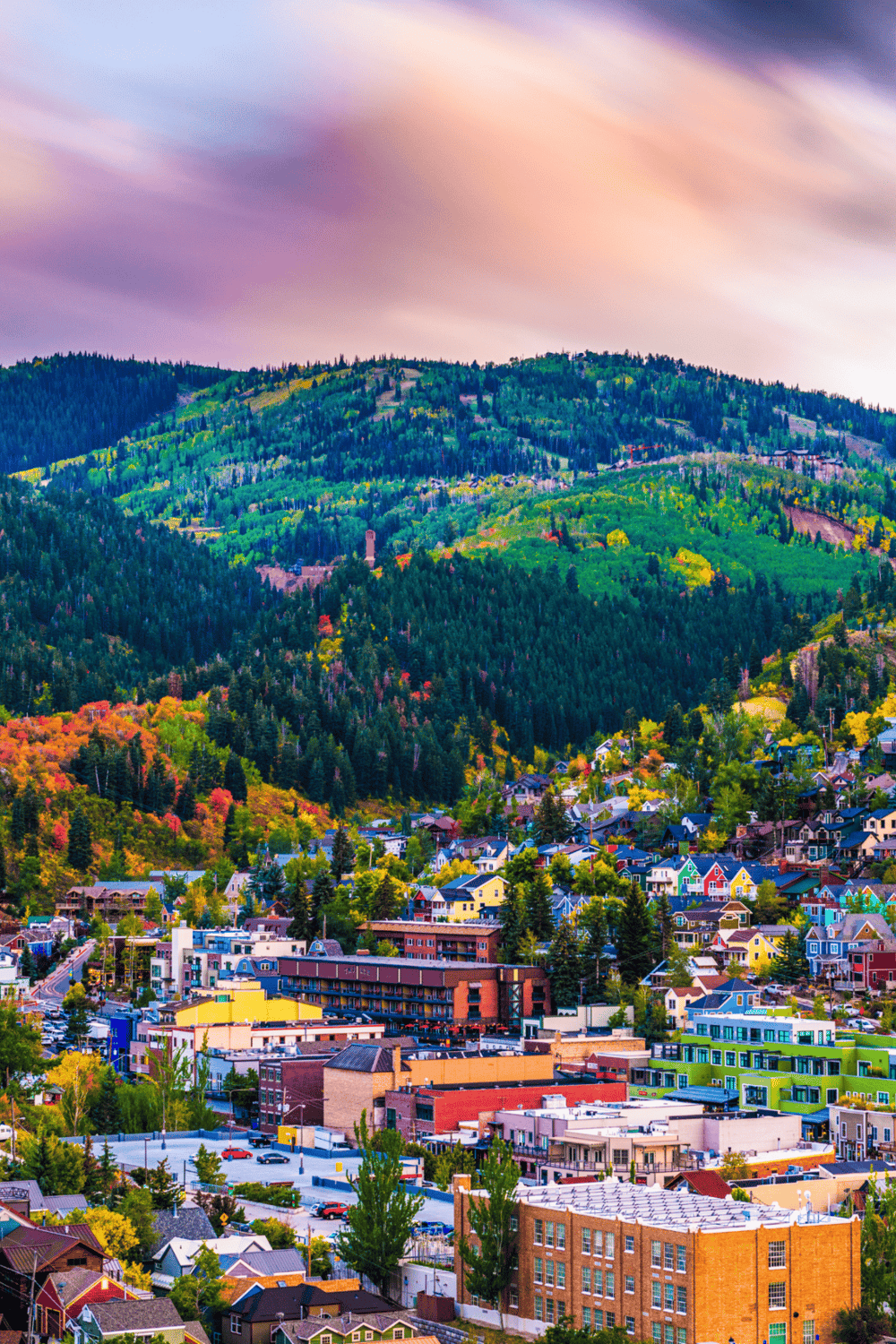Colorful mountain town surrounded by lush green forests and vibrant fall foliage.