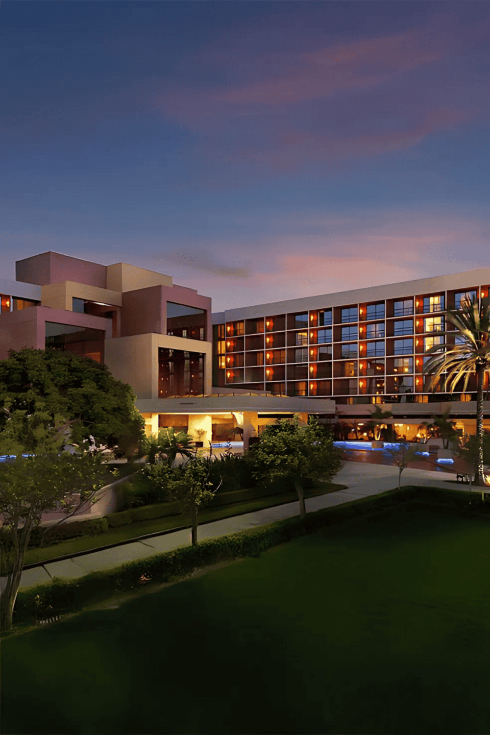 Luxurious hotel exterior at sunset with modern architecture and lush landscaping.
