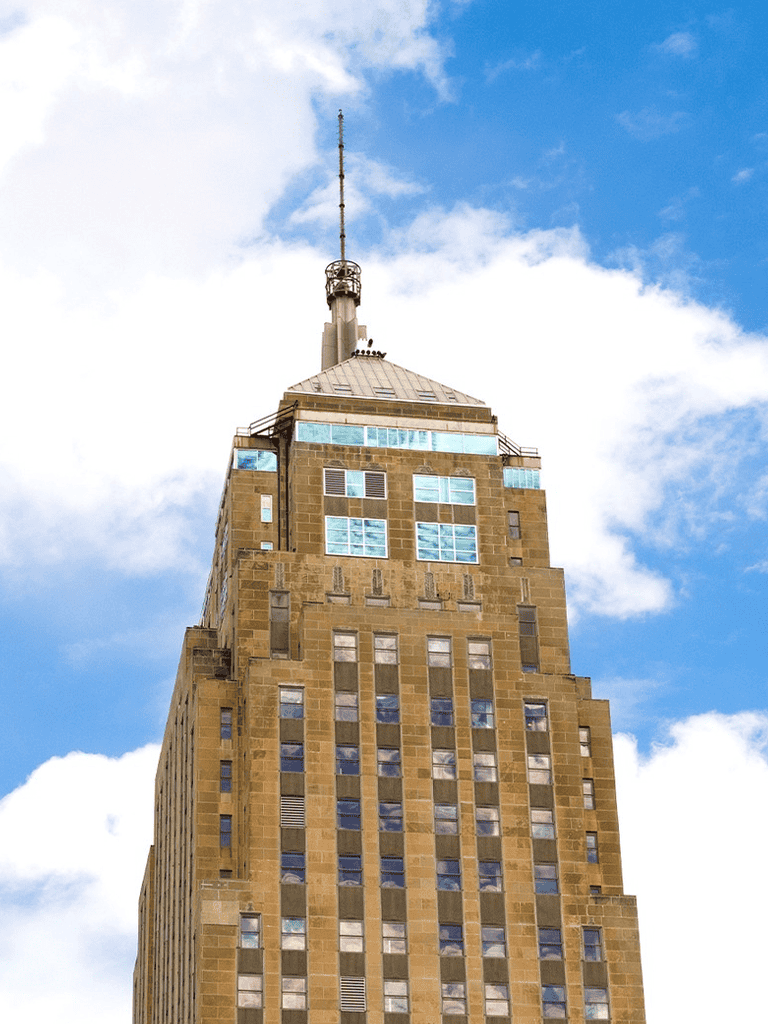 Art Deco Empire State Building with blue sky and clouds in New York City.