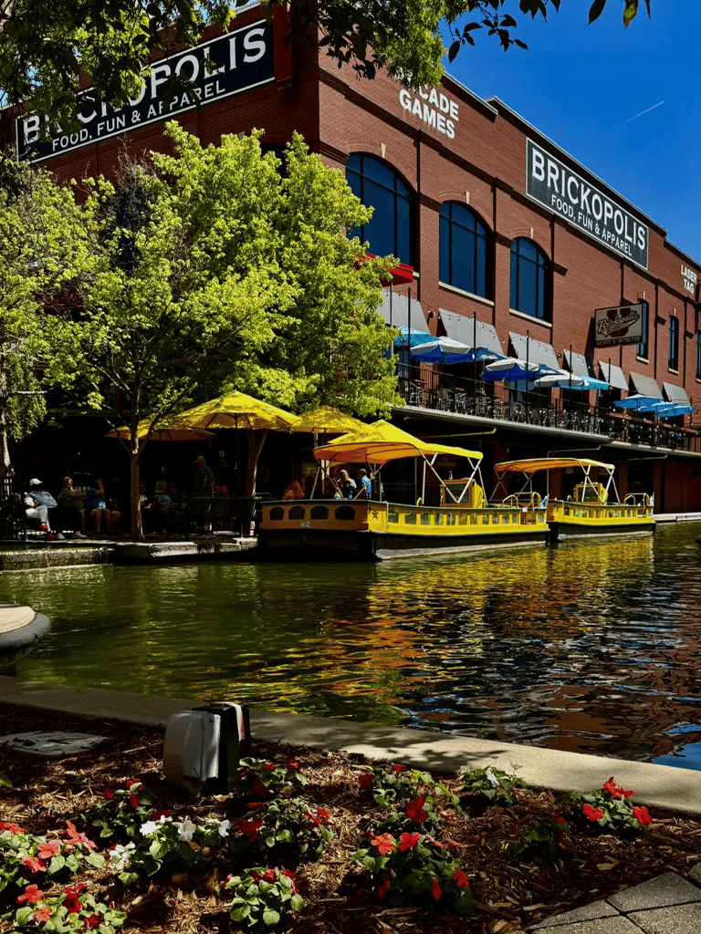 Boats docked along a scenic waterway outside Brickopolis arcade in a lively downtown area.