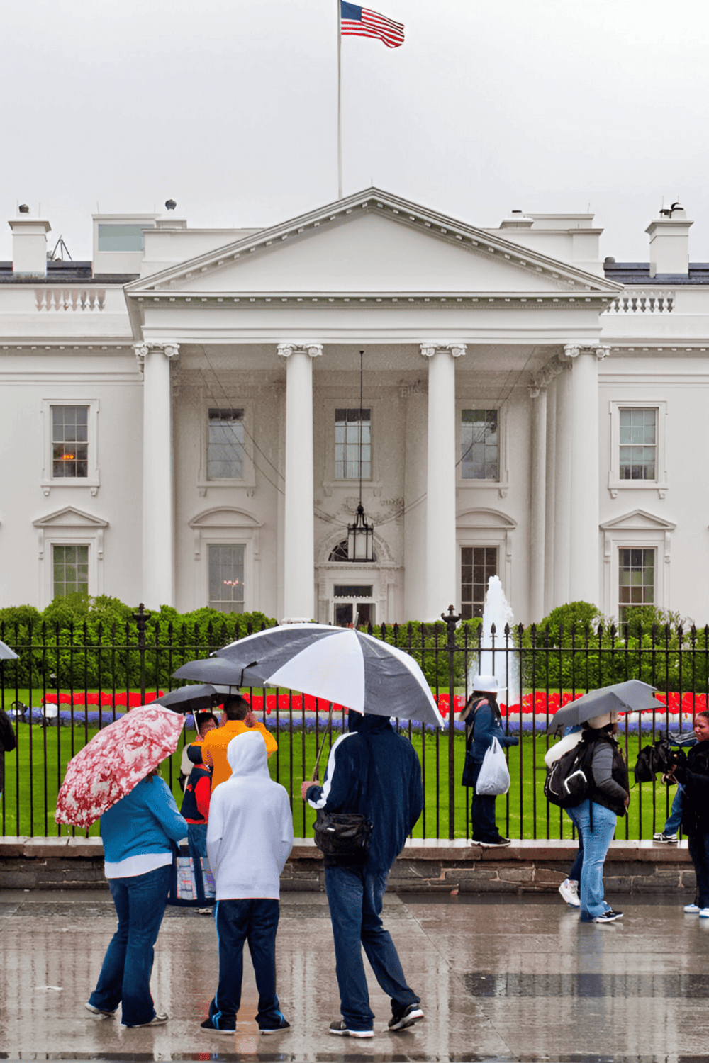 Historic White House with visitors and umbrellas during rainy day in Washington D.C.