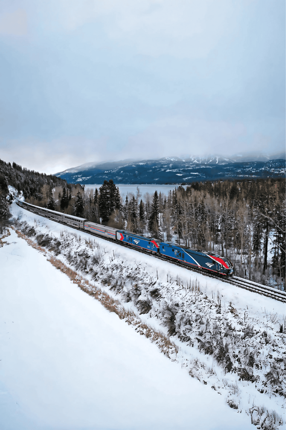 Historic train traveling through snowy landscape in the mountains.