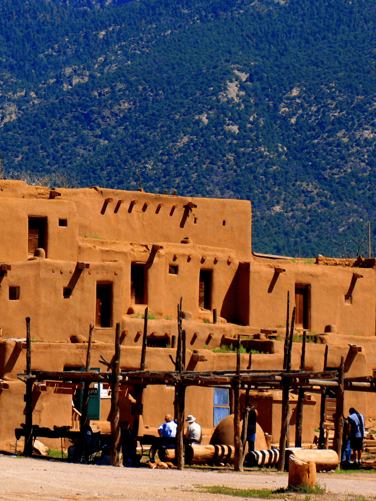 Ancient Pueblo adobe buildings in Santa Fe, New Mexico, on a sunny day with tourists exploring.
