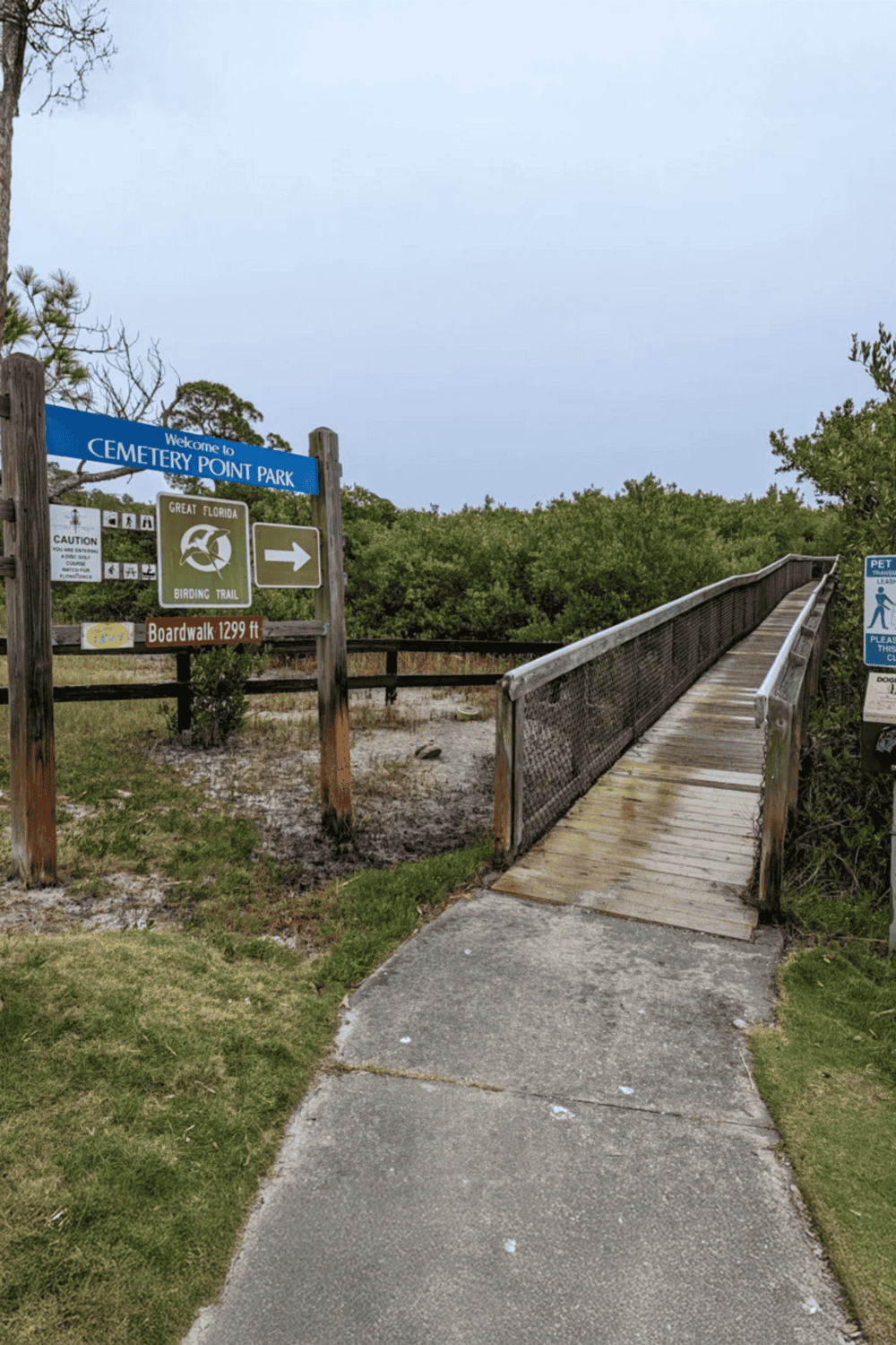 Boardwalk entrance at Cemetery Point Park, Florida, with signage for birding trail and park info.