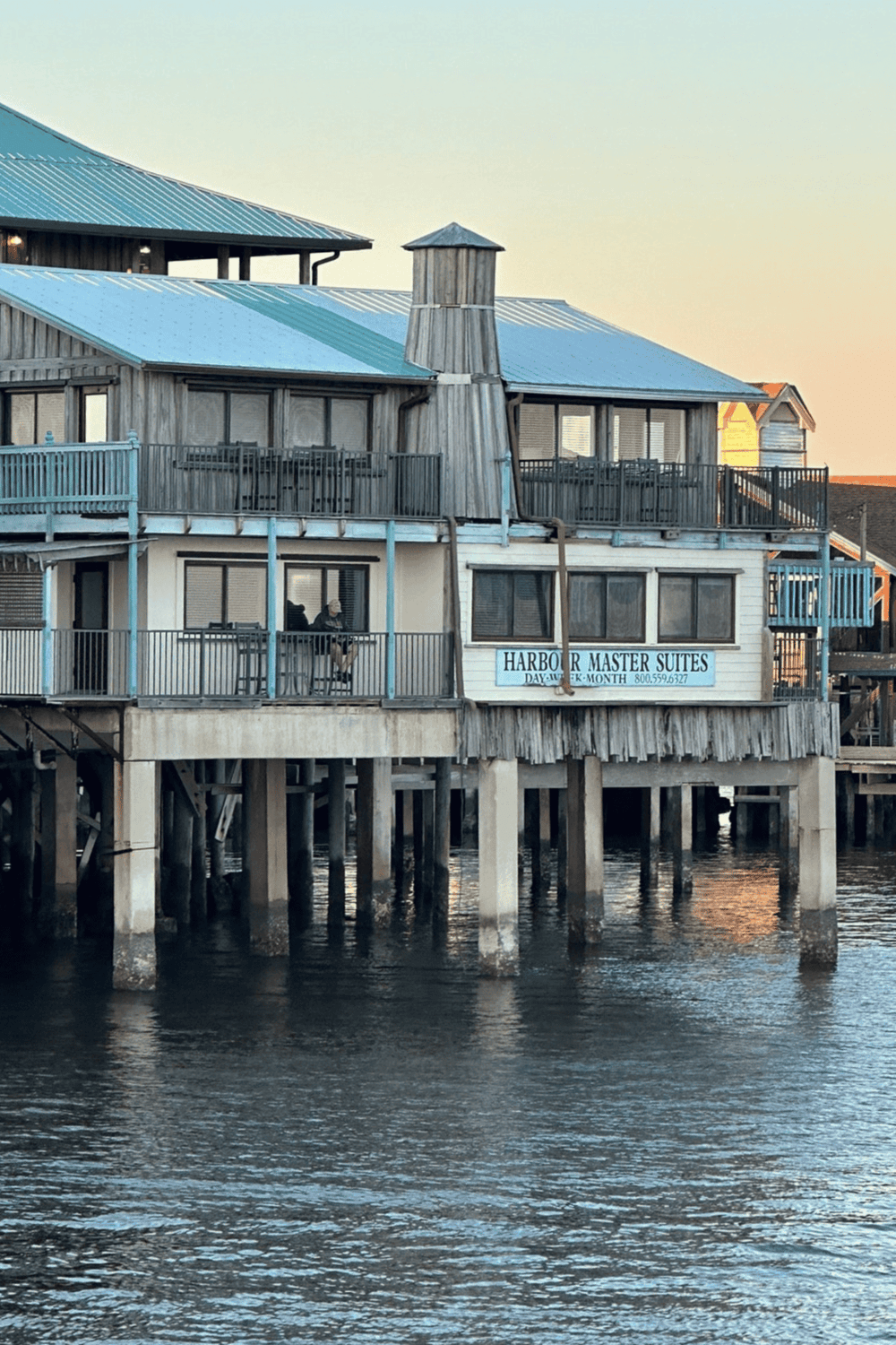 Seaside waterfront hotel building on stilts with a metal roof and nautical signage.