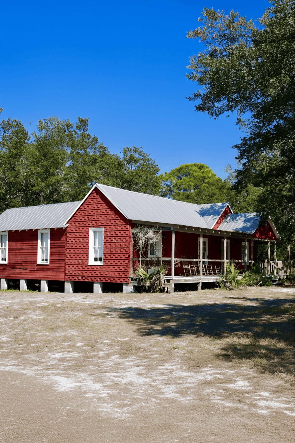 Cozy red cabin surrounded by trees against clear blue sky, ideal for outdoor retreats and nature escapes.