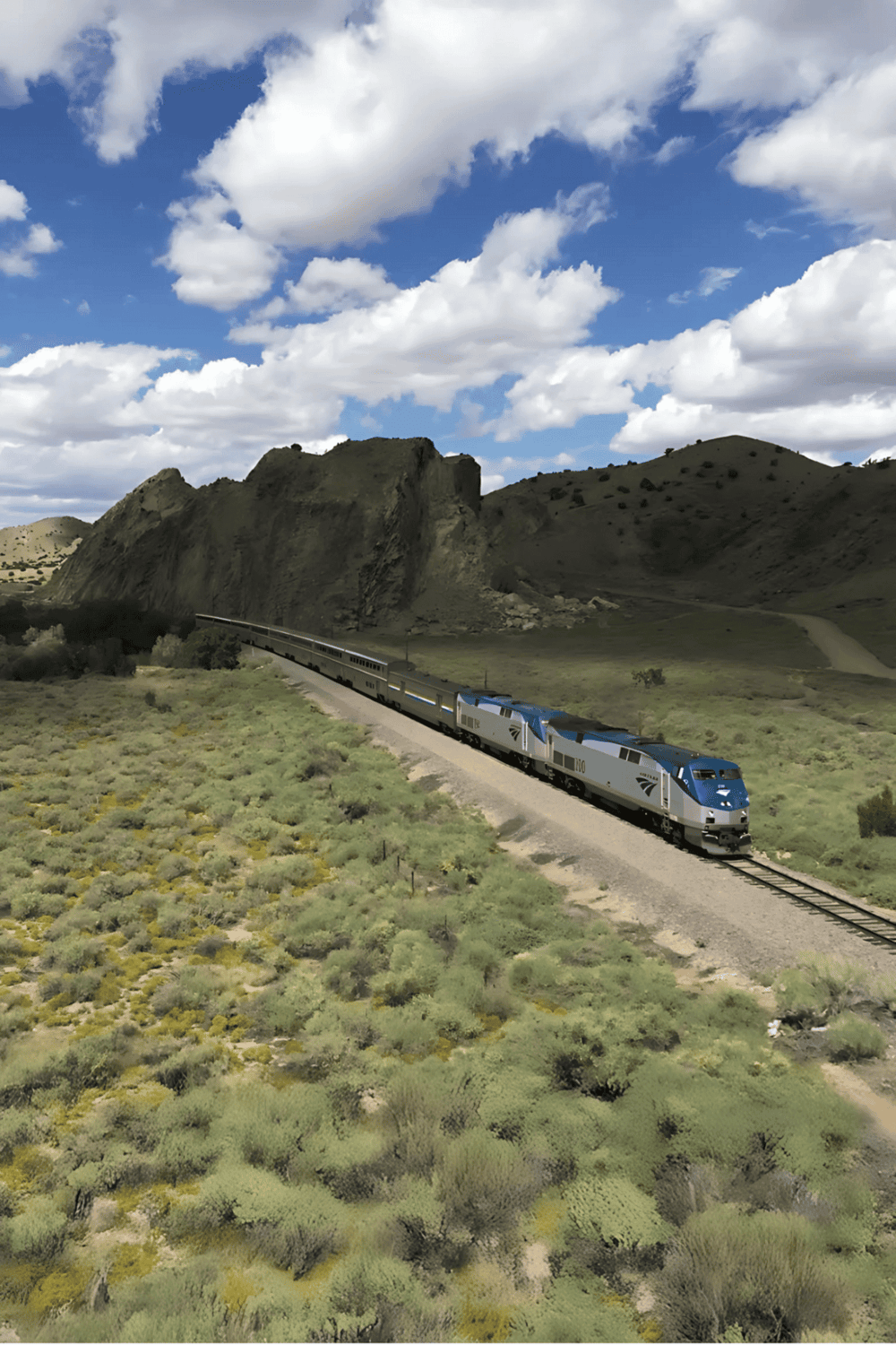 High-speed train traveling through scenic mountainous landscape with blue sky and clouds.
