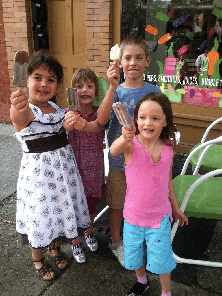 1. Kids enjoying ice cream outside a colorful shop, family-friendly, summer fun, dessert, children's happiness.