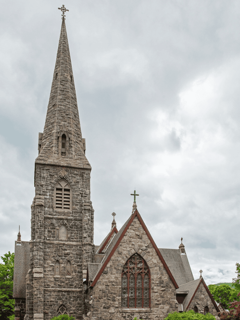 Historic stone church with tall steeple and stained glass windows.