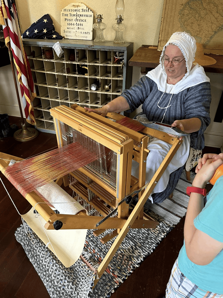 Traditional jacquard loom used for weaving fabric demonstration.