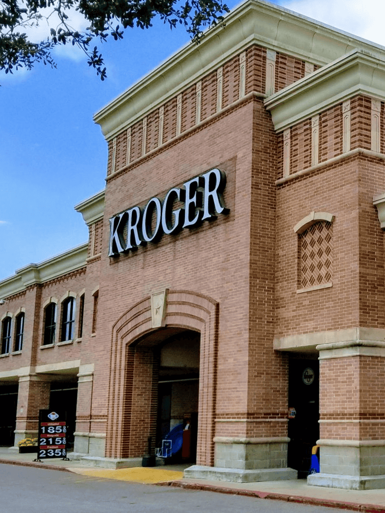 Kroger grocery store exterior, brick building with store signage, shopping entrance, and nearby parking.