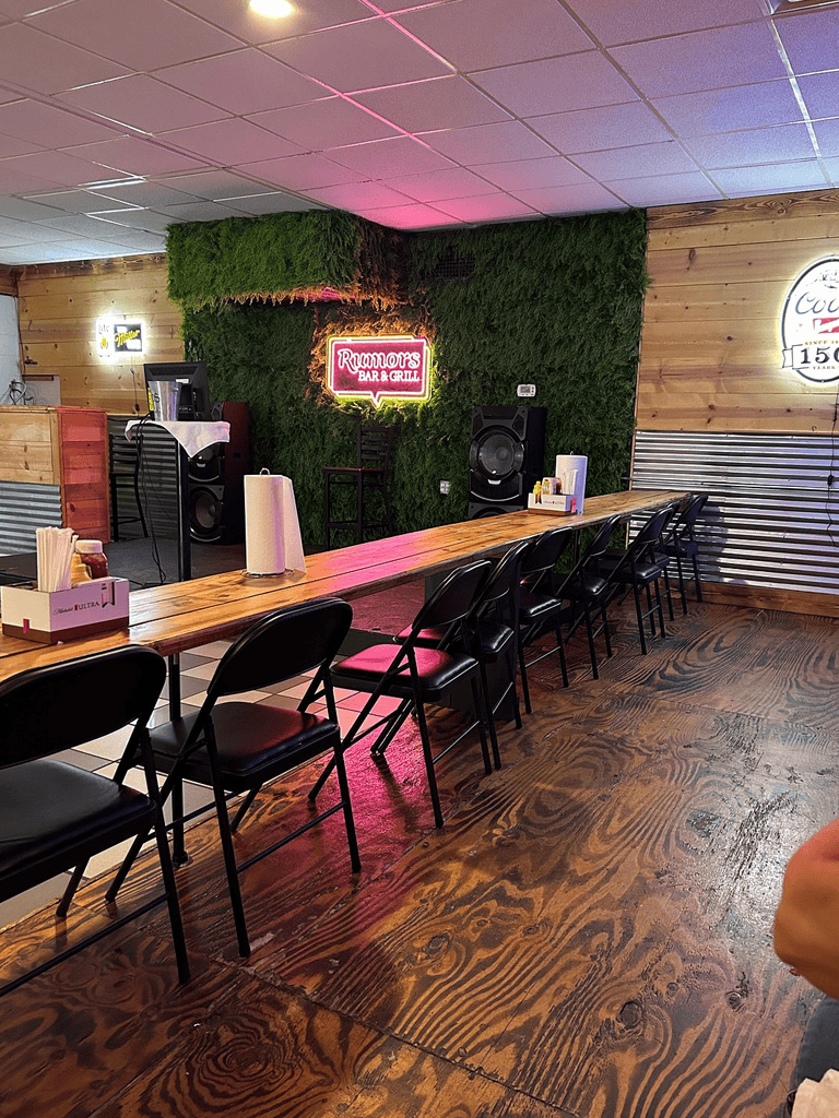 Rooftop bar with neon sign, live music setup, wooden decor, and cozy atmosphere for guests.