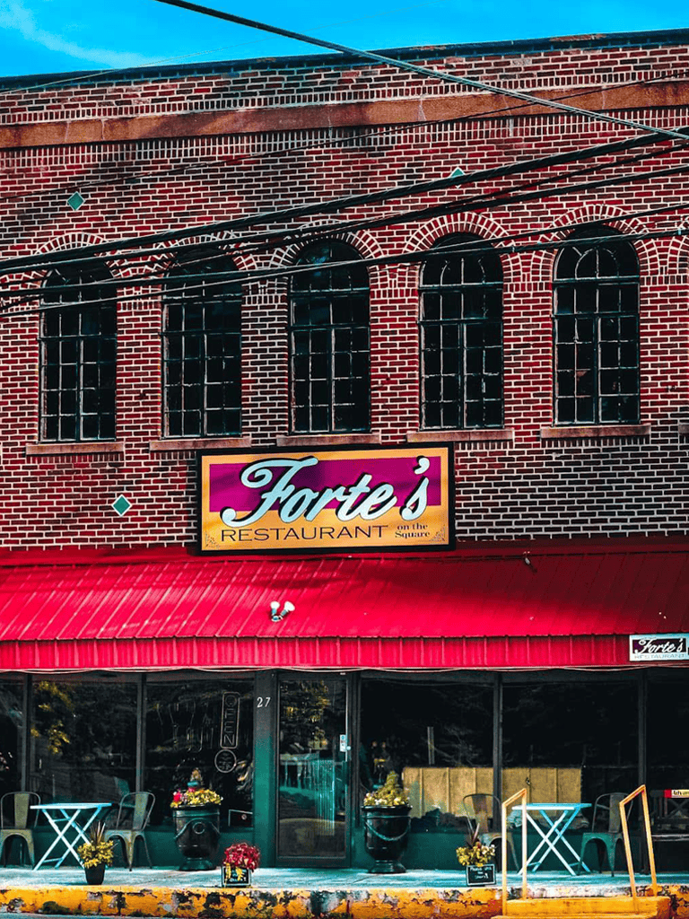 Charming brick restaurant exterior with vibrant sign and inviting patio dining area.