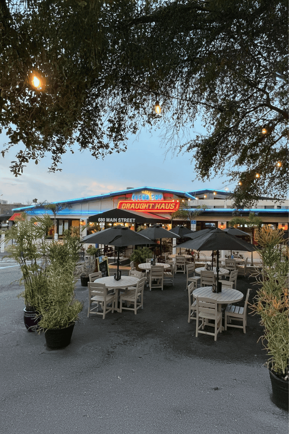 Outdoor dining at a restaurant with neon signs and string lights, inviting atmosphere and patio seating.