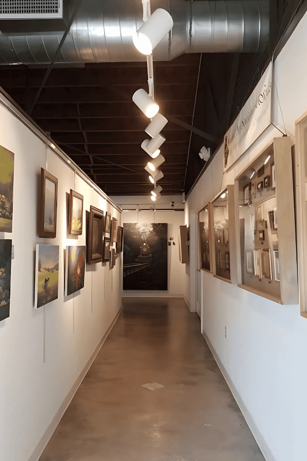 Colorful art gallery exhibit with framed paintings on white walls and overhead lighting.