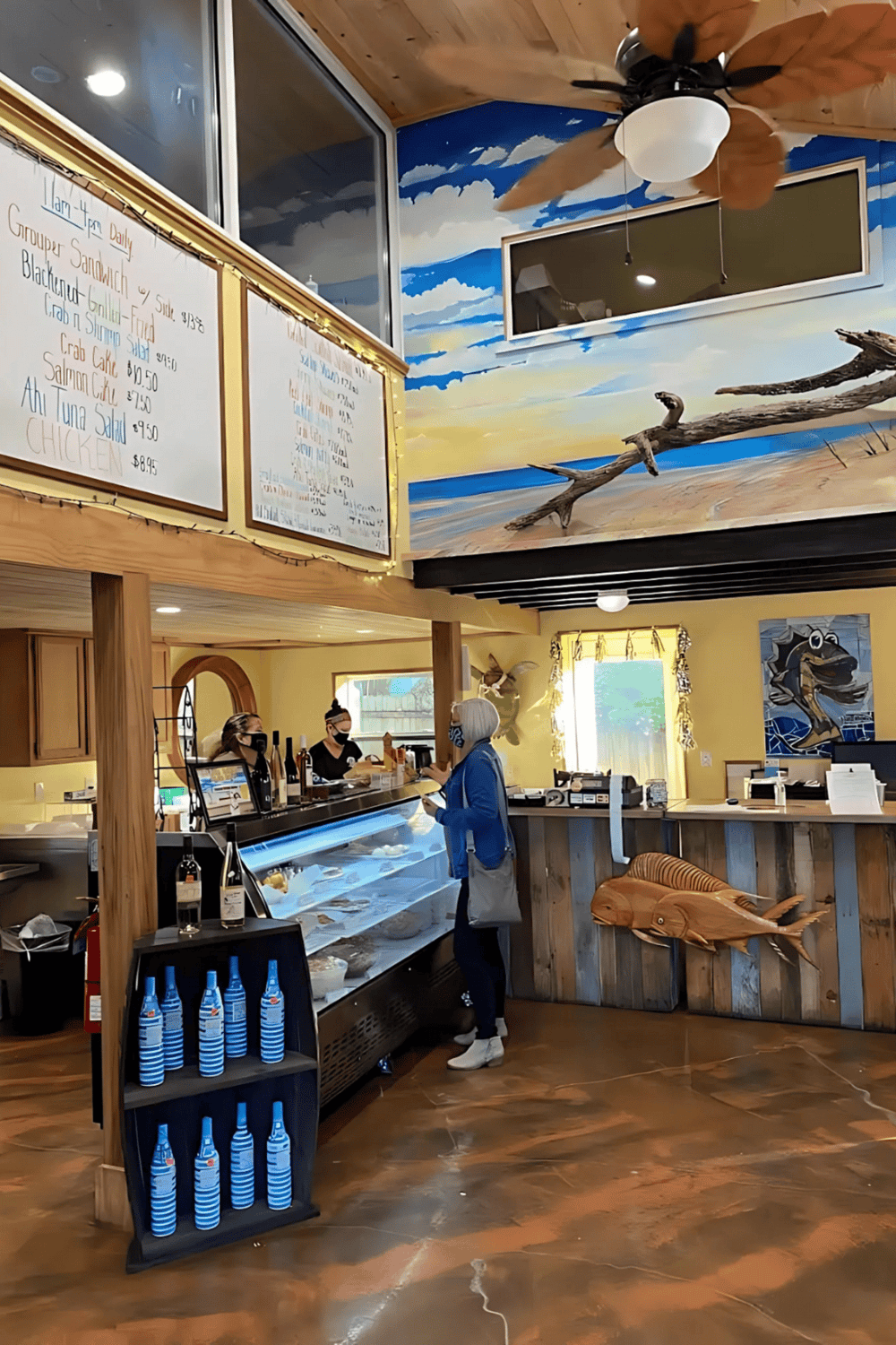 - Colorful ocean-themed restaurant interior with ceiling fan and wall art.