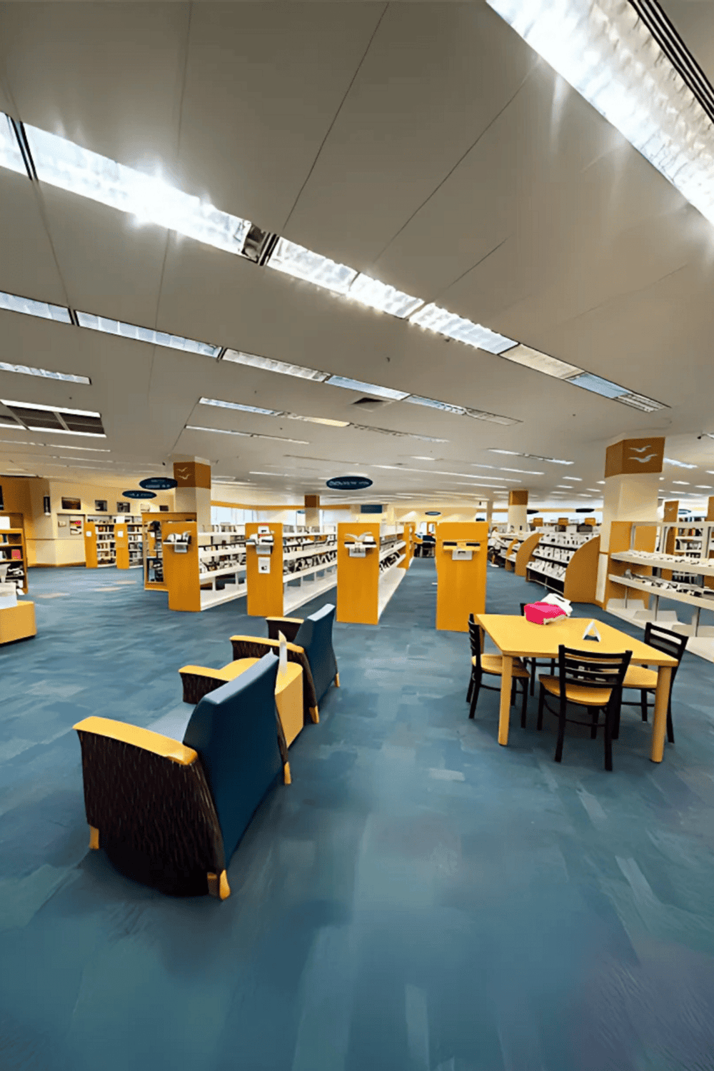 Bright modern library interior with bookshelves, reading tables, and comfortable chairs for studying.
