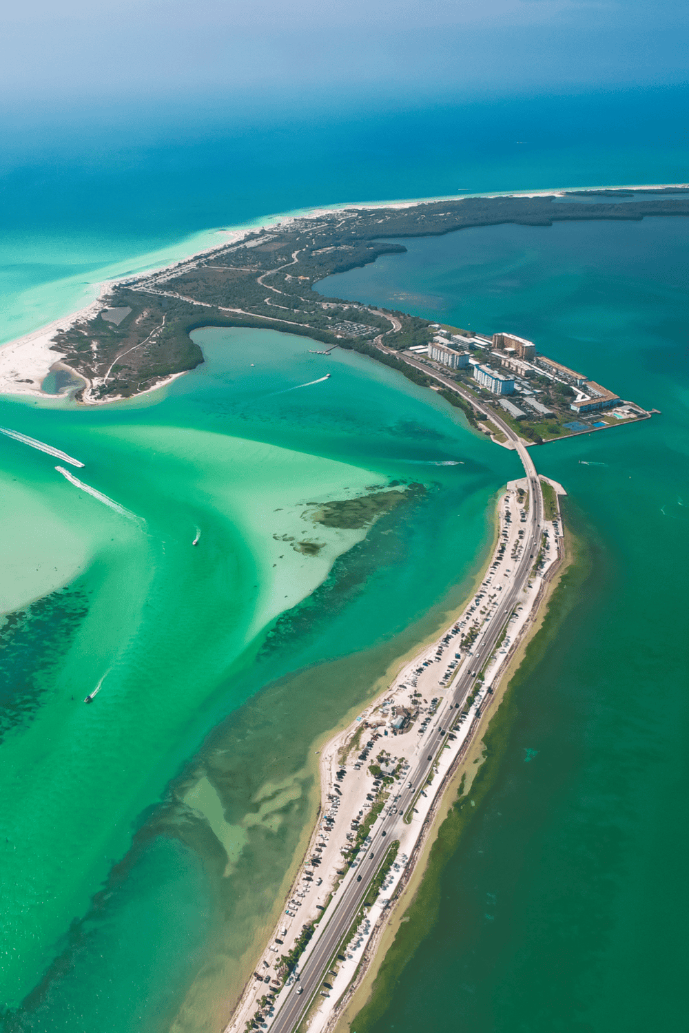 Aerial view of Quest for Directions waterfront resort with resort, beach, and turquoise waters.