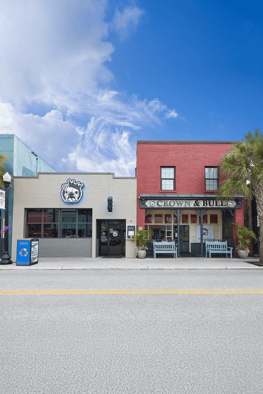 Vintage pub exterior with bold signage and inviting seating, located on bustling city street with palm trees and blue sky.