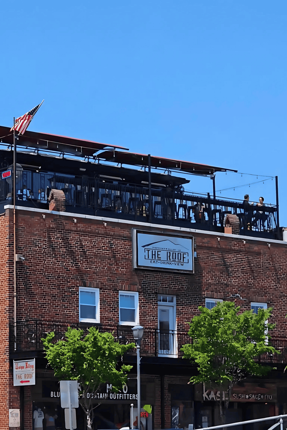 Outdoor rooftop bar with city view at The Roof, offering drinks, dining, and scenic skyline scenery.