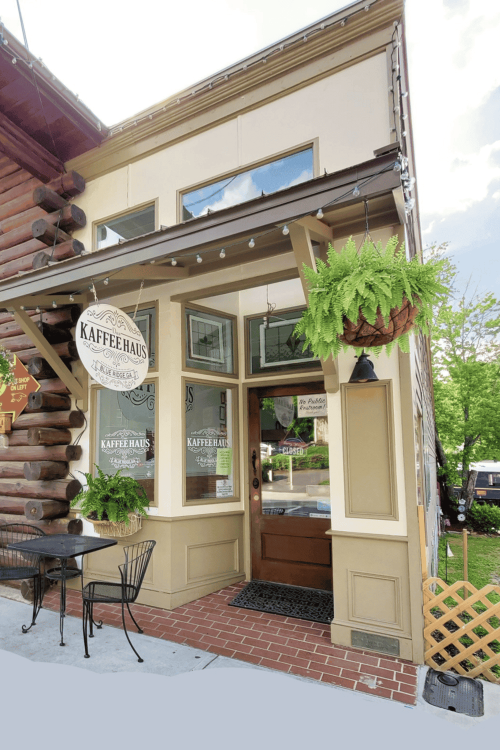 Cozy coffee shop exterior at KafeeHaus with outdoor seating and hanging plants, perfect for relaxing and enjoying quality coffee.
