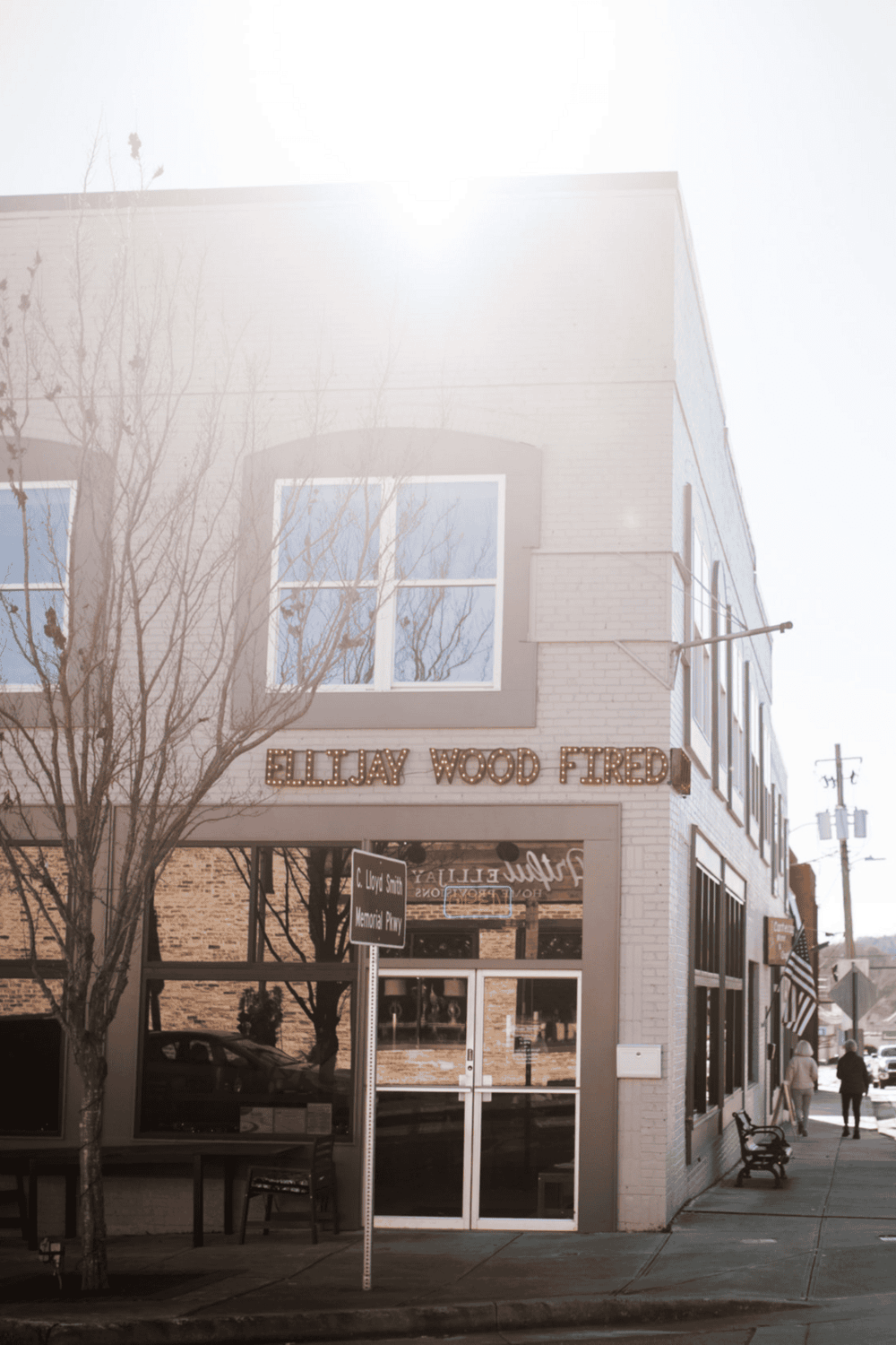 1. Modern brick building with "Elijah Wood Fired" sign, city sidewalk, and pedestrians.