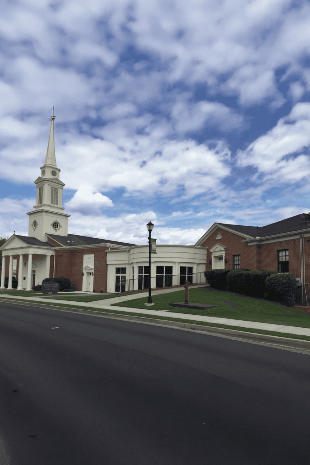 Bright church building with white steeple and brick walls under a cloudy sky, part of Quest For Directions.