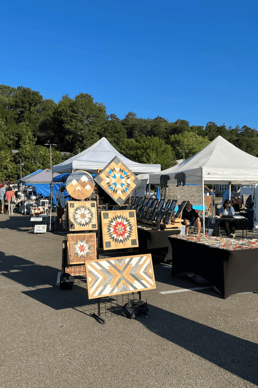 Colorful quilt artwork displayed at outdoor craft fair offering unique handmade crafts and art.