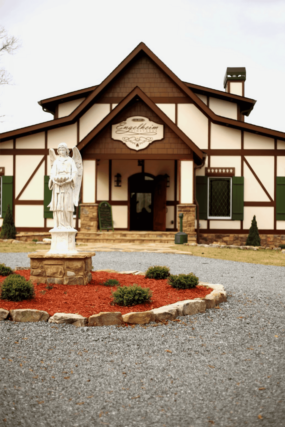 Charming Tudor-style building with gardens, statue, and inviting entrance, perfect for guiding directions.