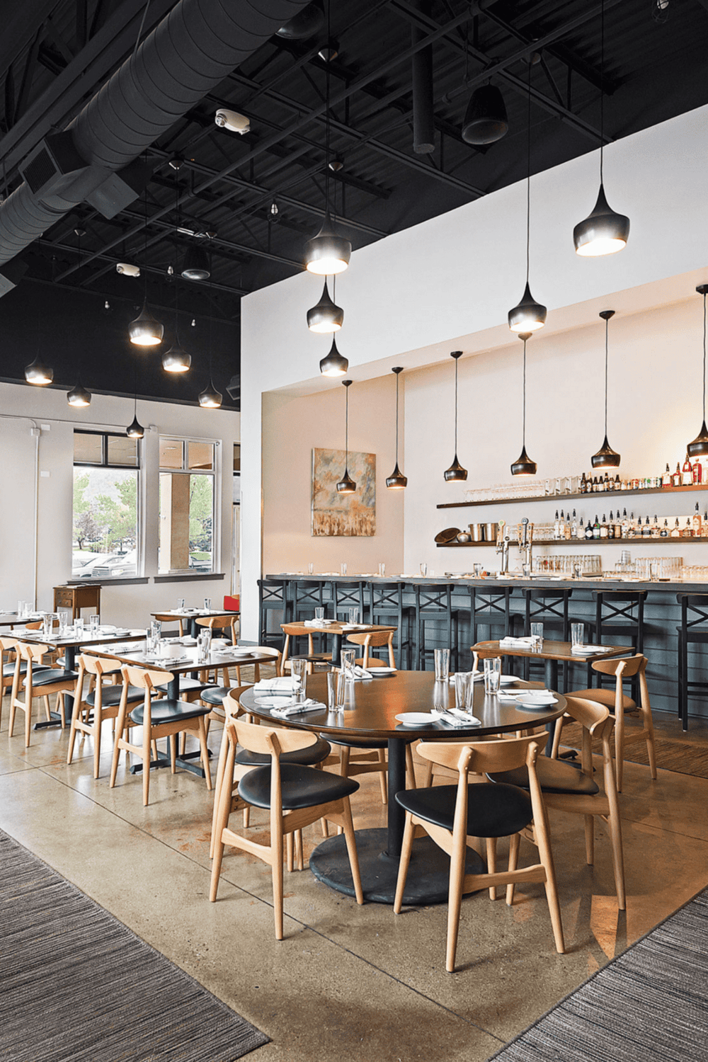 Modern restaurant interior with stylish wooden chairs and black accents, perfect for dining out and social gatherings.