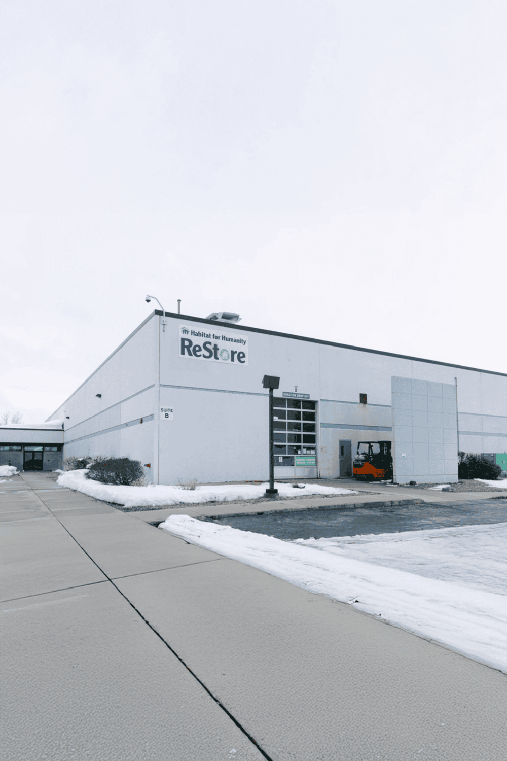 1. Modern Habitat for Humanity ReStore building with snow and outdoor lighting.