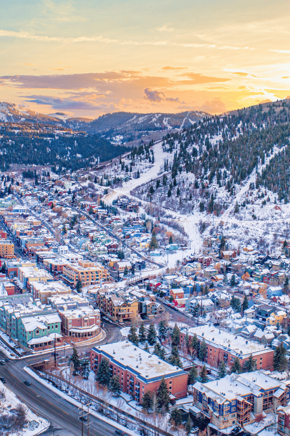 Snowy mountain town with colorful buildings and ski slopes in the background, beautiful sunset lighting, perfect for travel and winter adventure.