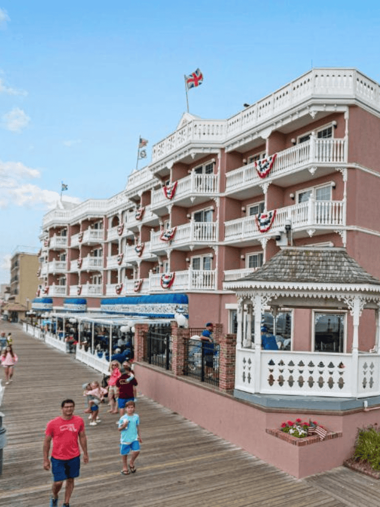 Sunny seaside hotel with Victorian architecture and festive bunting, ideal for beach vacations and family getaways.