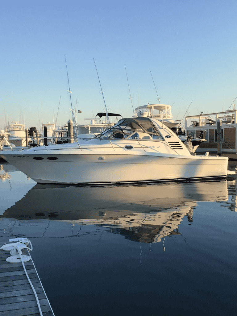 Luxury motor yacht docked at marina with fishing boats, ideal for marine adventure trips.