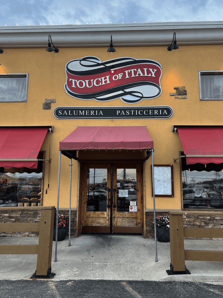 Stylish Italian restaurant entrance with "Touch of Italy" sign, outdoor decor, and welcoming ambiance.