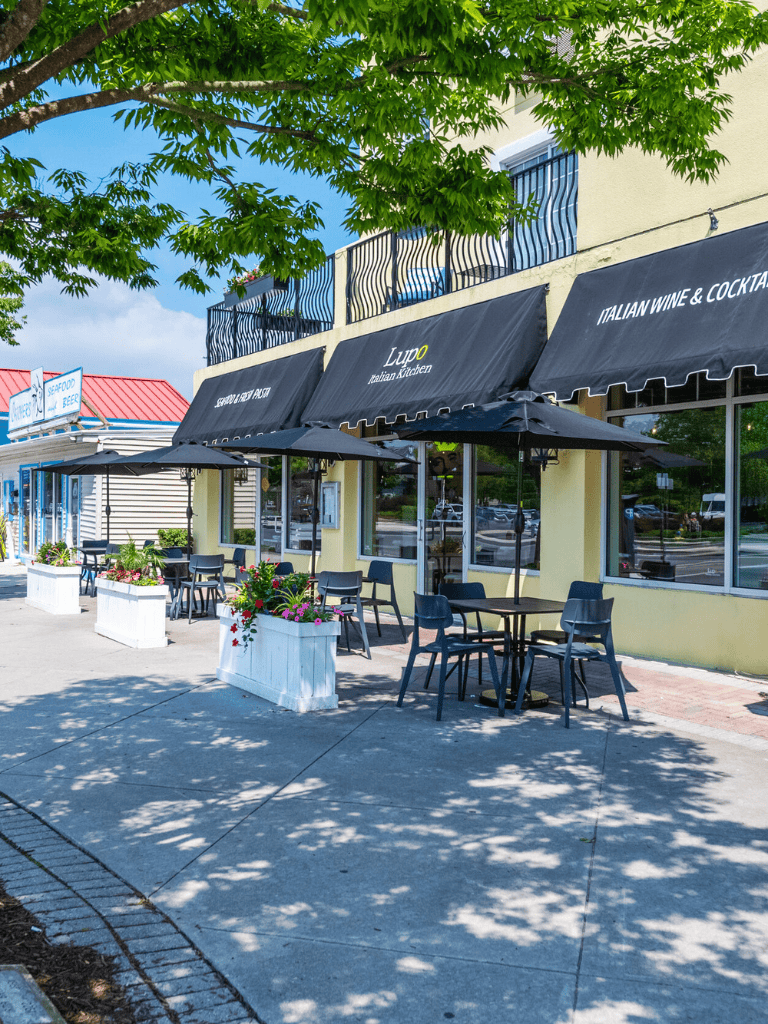 Outdoor patio of Italian restaurant with black umbrellas and potted flowers, ideal for dining and relaxation.