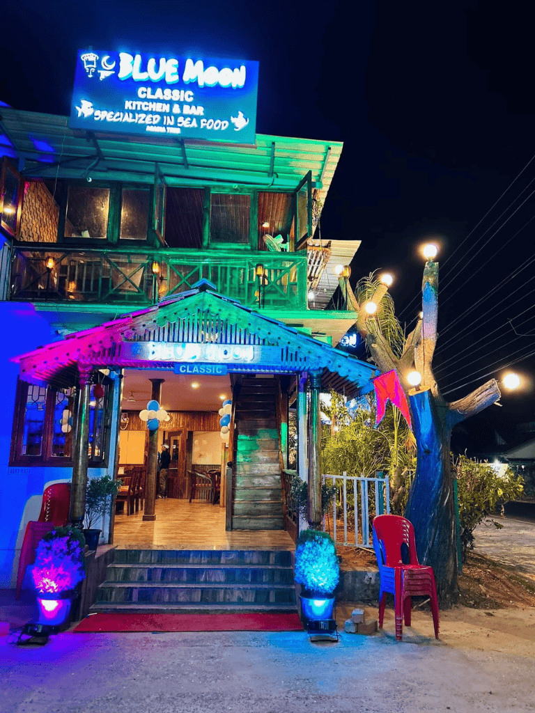 Blue Moon restaurant exterior at night with colorful neon lights and tropical decor.