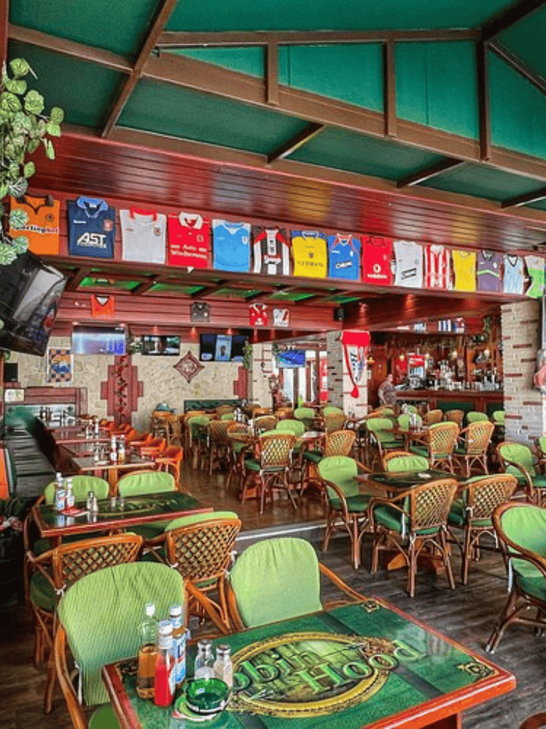 Colorful sports-themed restaurant interior with green cushioned seating and sports memorabilia decor.