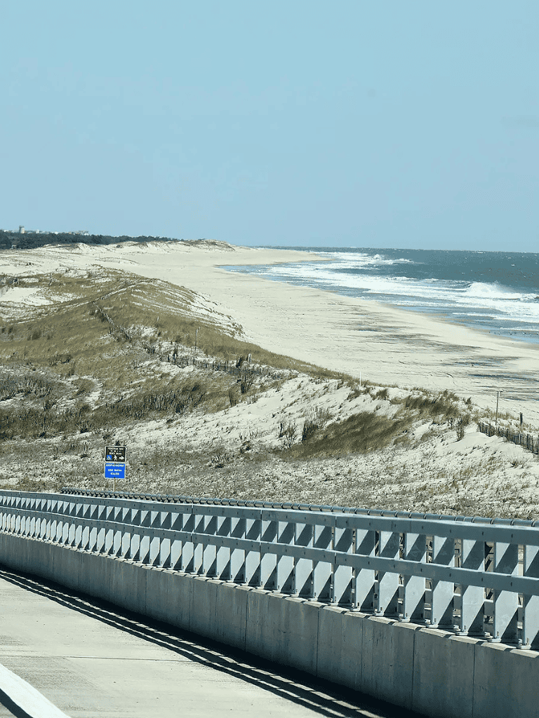 Seaside coastal highway view with beach dunes and ocean waves, scenic route along the coast for travel and outdoor adventures.