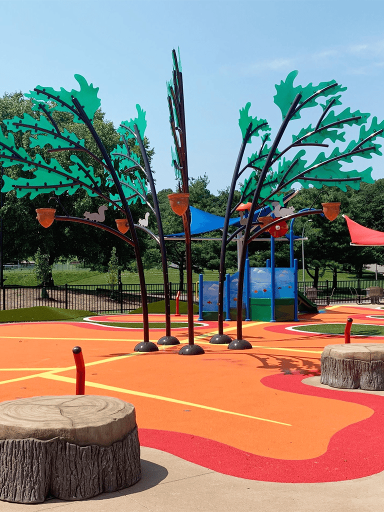 Vibrant kids' playground with colorful trees and shade sails, perfect for family fun and outdoor recreation.