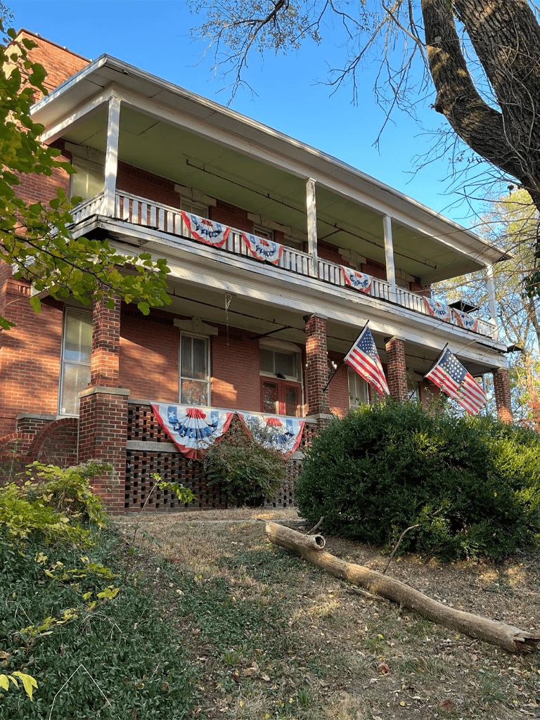 Patriotic decorated historic brick house with American flags and bunting for US holiday celebrations.