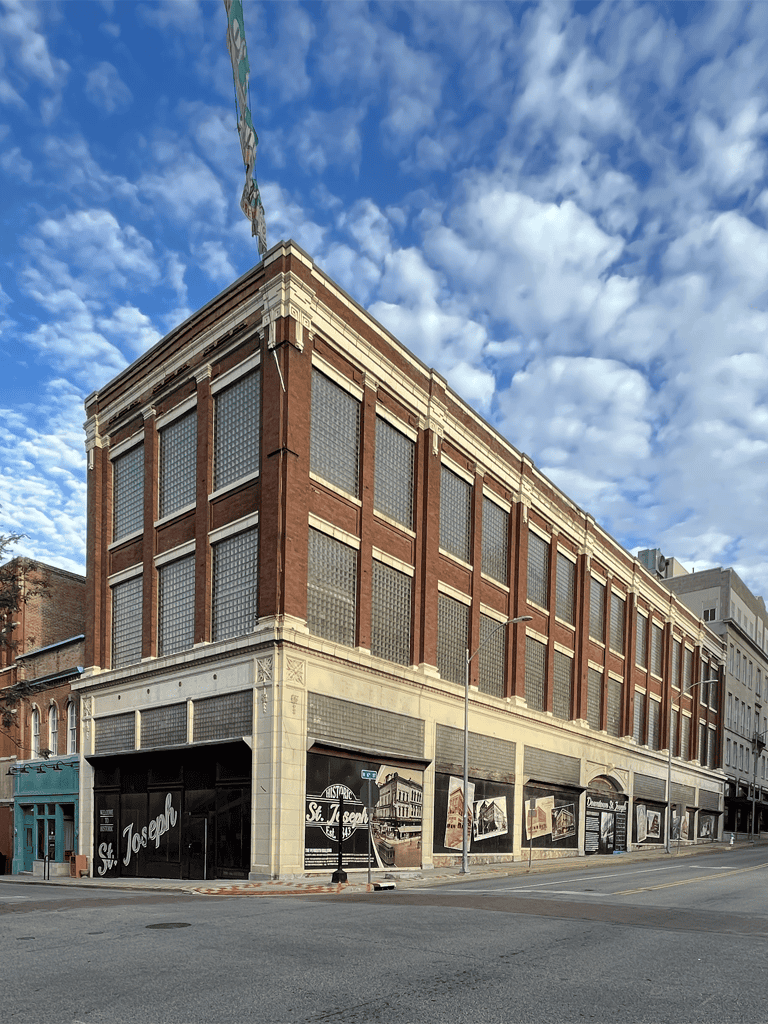 Historic brick building with large glass block windows under a cloudy sky.