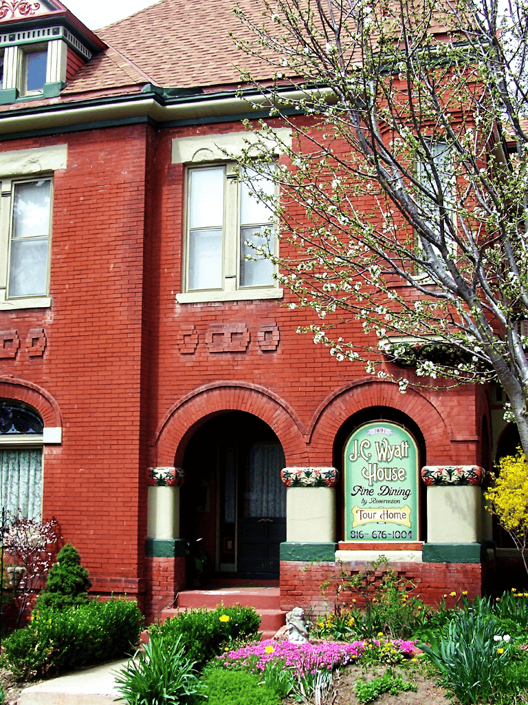 Charming historic red brick house with lush garden and J.C. Wyatt House sign. Perfect for visiting downtown tour home.