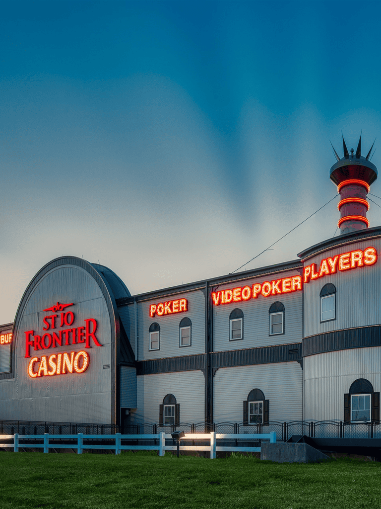 Vivid image of St. Jo Frontier Casino with neon signs for poker and video poker in the evening.