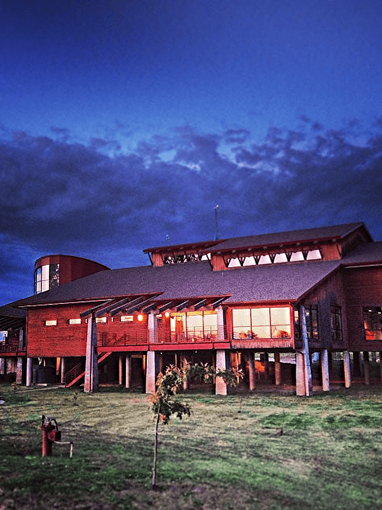 Modern wooden building with large glass windows and outdoor lighting during twilight at Quest For Directions.