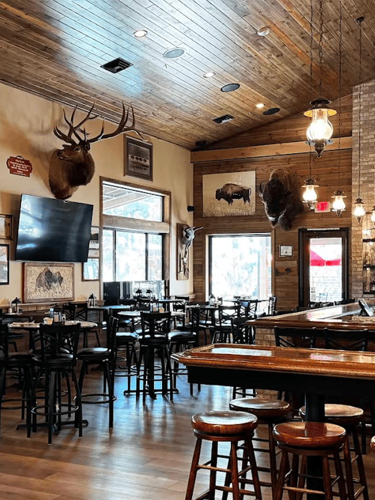 Taxidermy mounted animal heads in rustic restaurant interior, wooden ceiling and walls, hunting lodge decor.