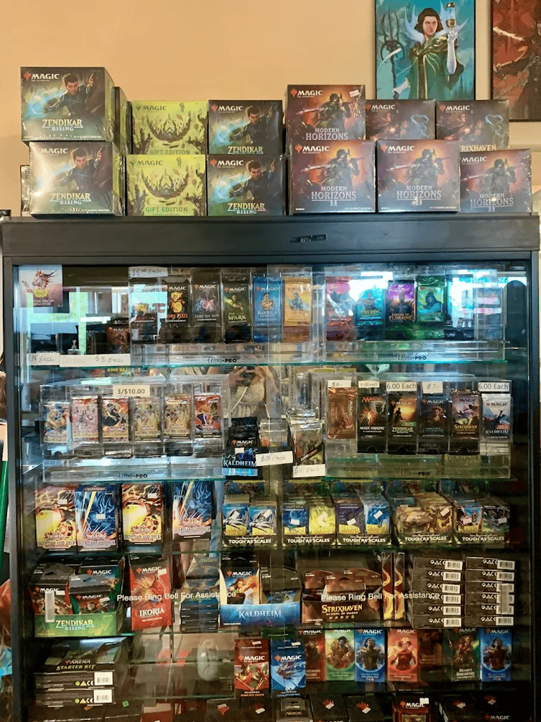 Alternate text: Magic: The Gathering booster packs and boxes on display at QuestForDirections.